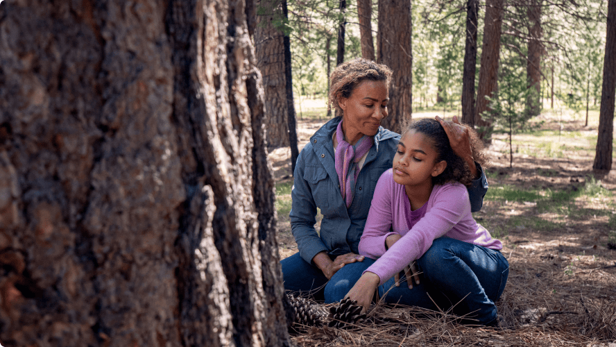 mom and daughter sit at a memorial tree talking about a better ending