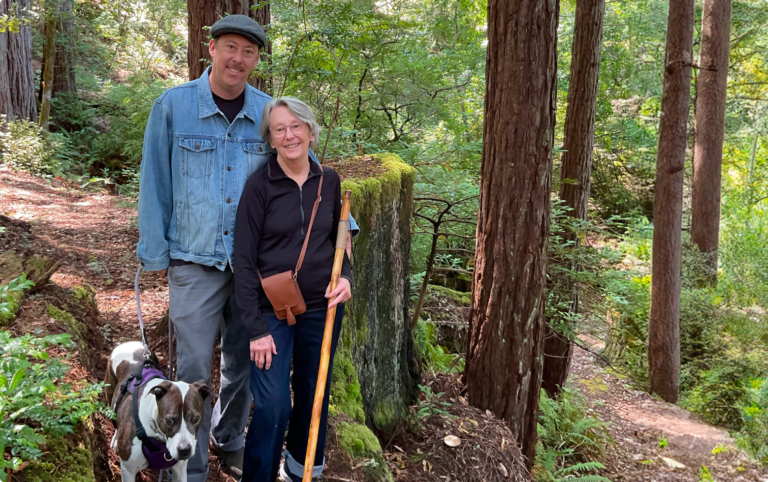 A family stands by a towering redwood tree in Better place forests Point arena, California