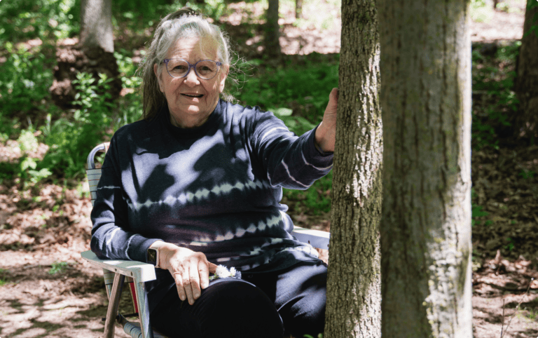 a woman sits by her husbands memorial tree in better place forests rock river memorial forest